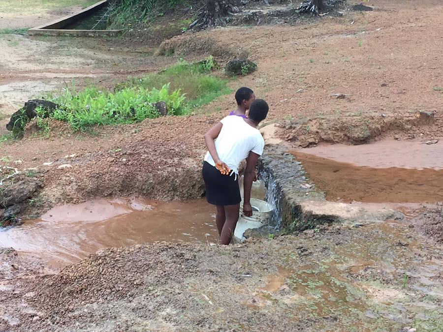 Nigerian children gather water in a bucket